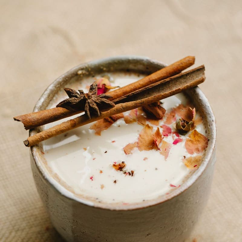 Cup of milky chai topped with rose petals and cinnamon