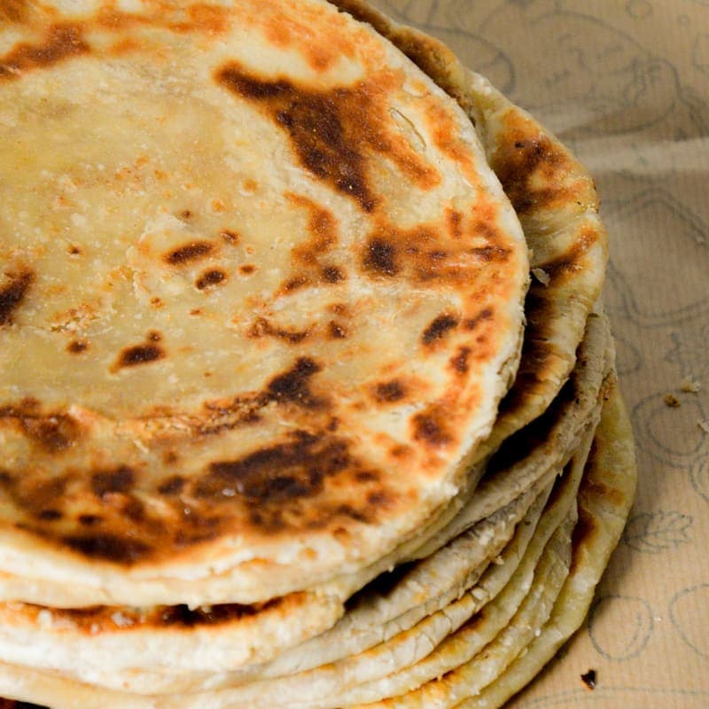 Stack of ghee-browned flatbreads on kraft paper